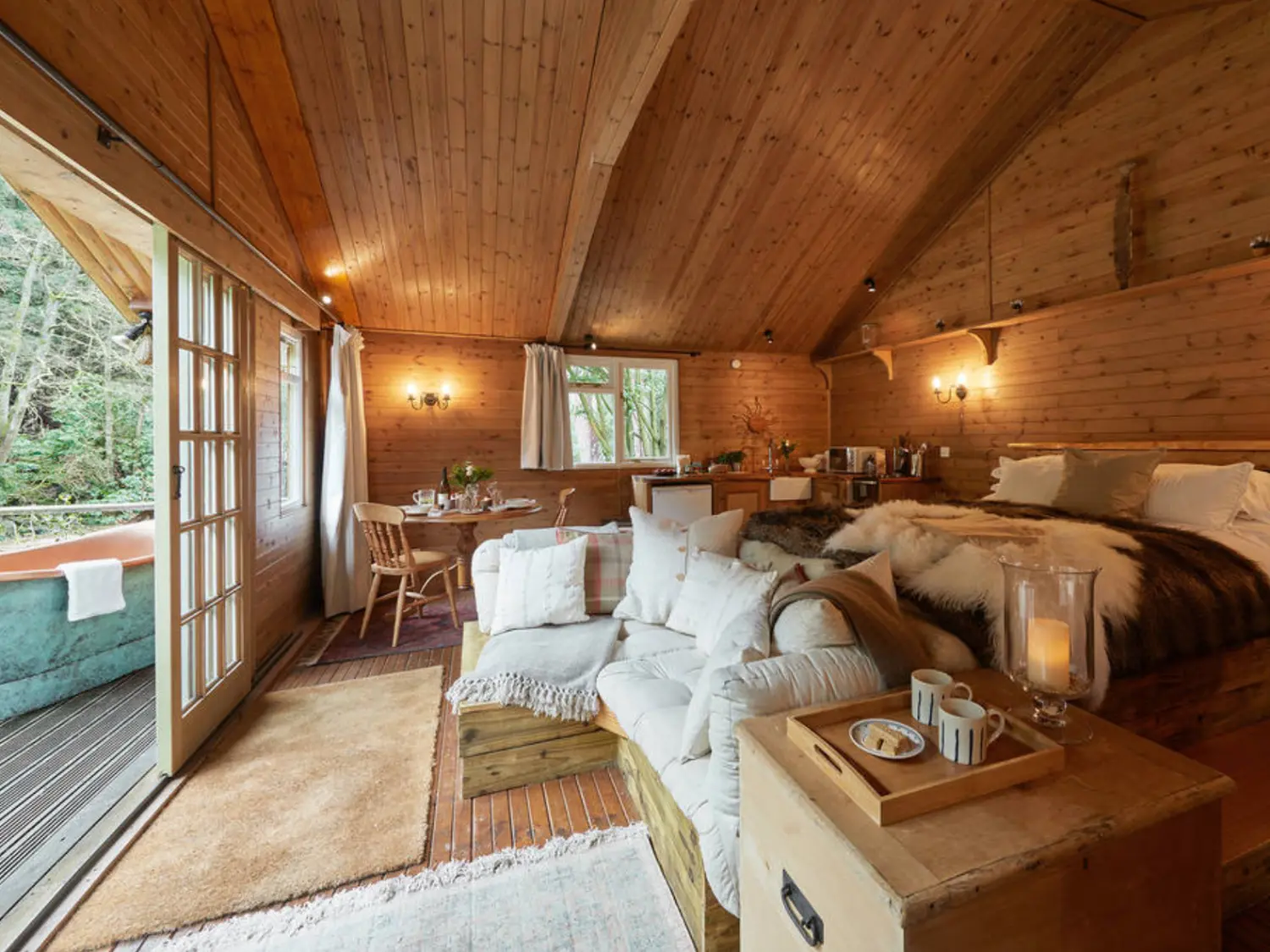 Living area and bedroom with hot tub on decking at The River Lodge.