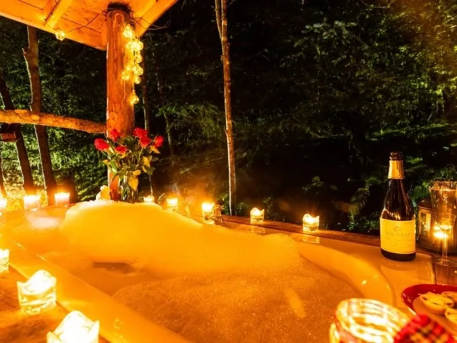 Outdoor soaking tub surrounded by candles, flowers, and prosecco at Squirrel’s Drey, Dreamcatcher's Cabin.