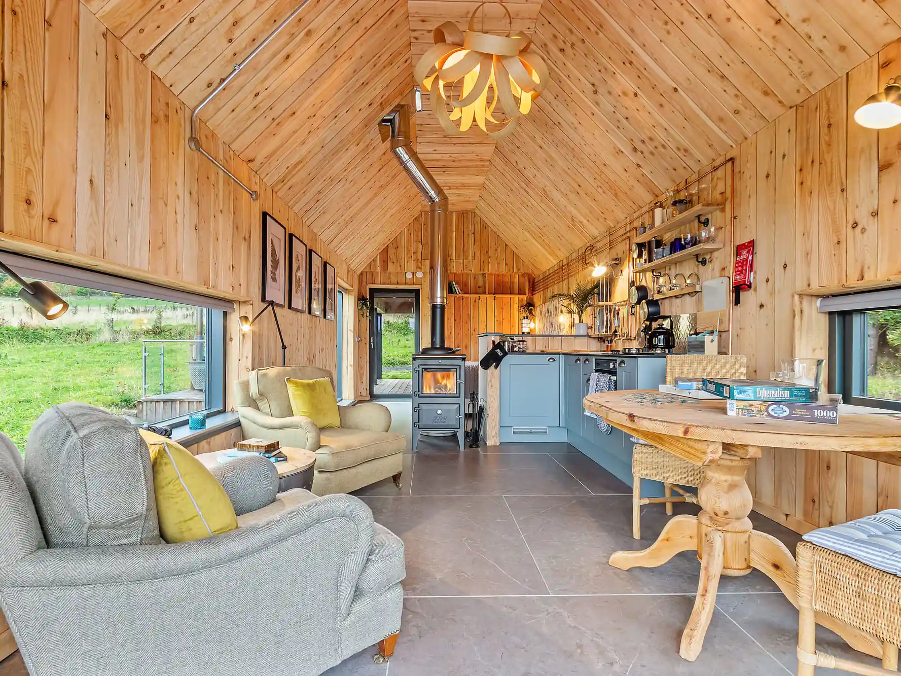 Wooden Interior of Bothan Dubh lodge at Outfield Cabins - picture shows the living room, kitchen and dining area and wood burner.