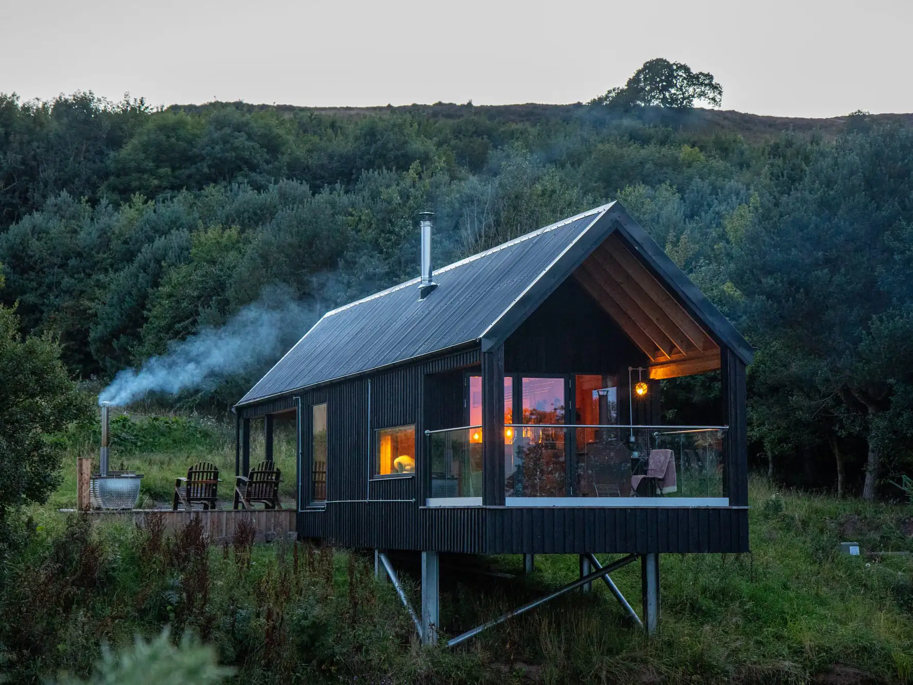 Exterior of Bothan Dubh Lodge at Outfield Cabins - picture shows cabin and outdoor seating area with hot tub.