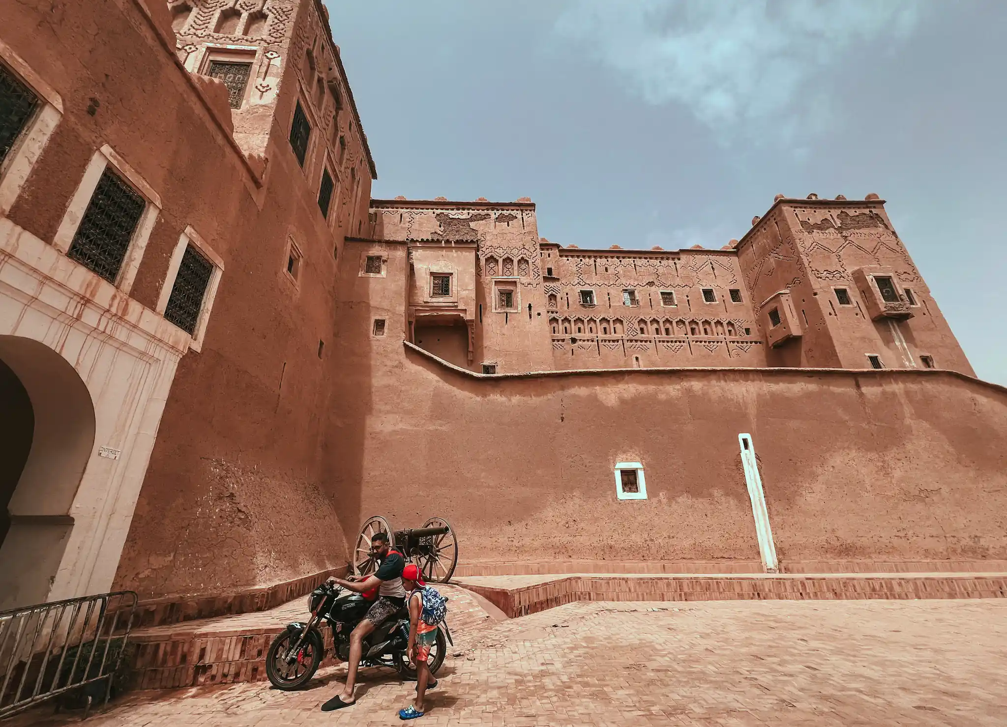 Man on motorcycle with son in front of Kasbah Taourirt in Ouarzazate.