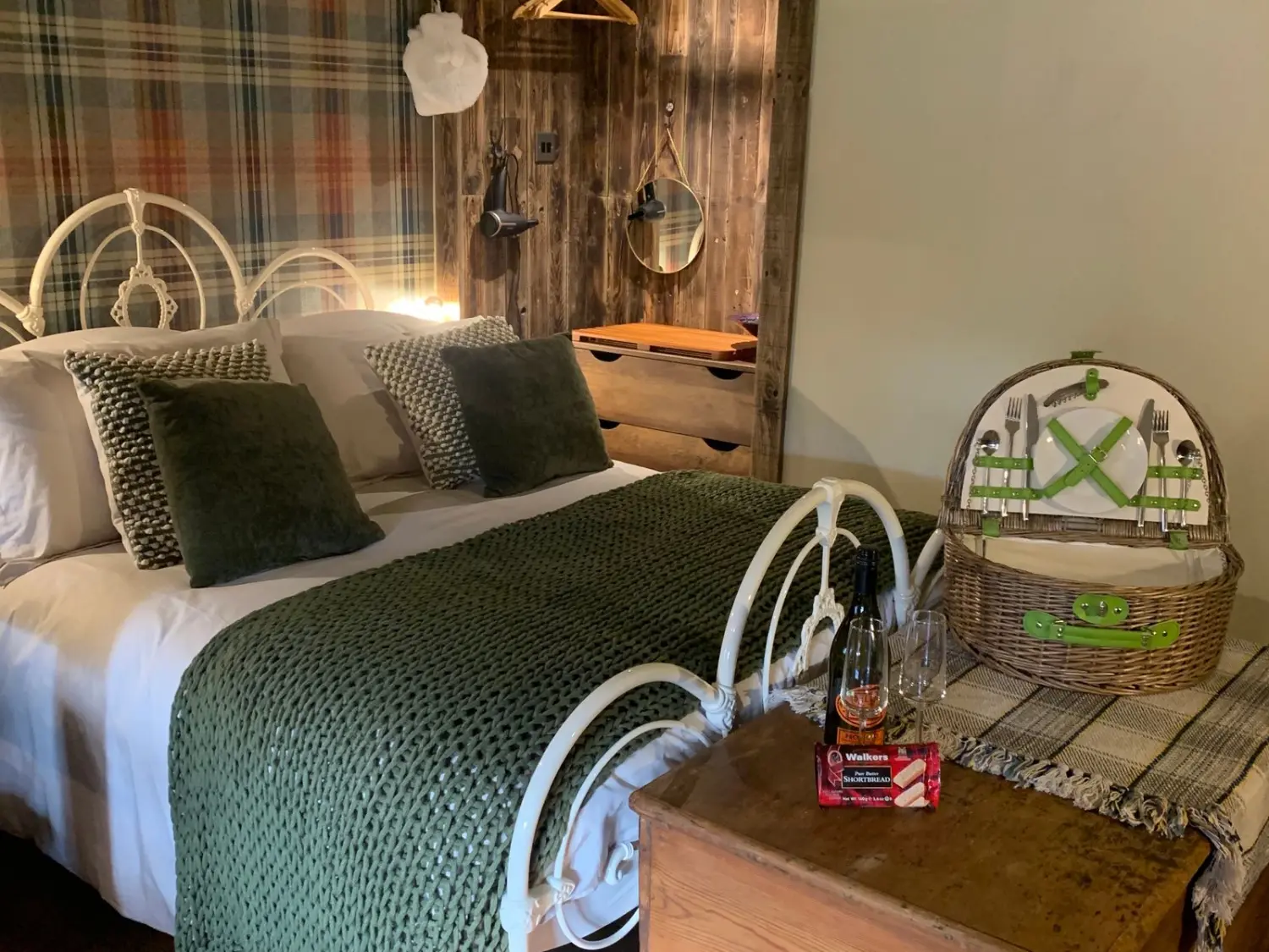 Watermill Nook Interior featuring double bed and a chest at the end of the bed with prosecco and picnic basket on top.