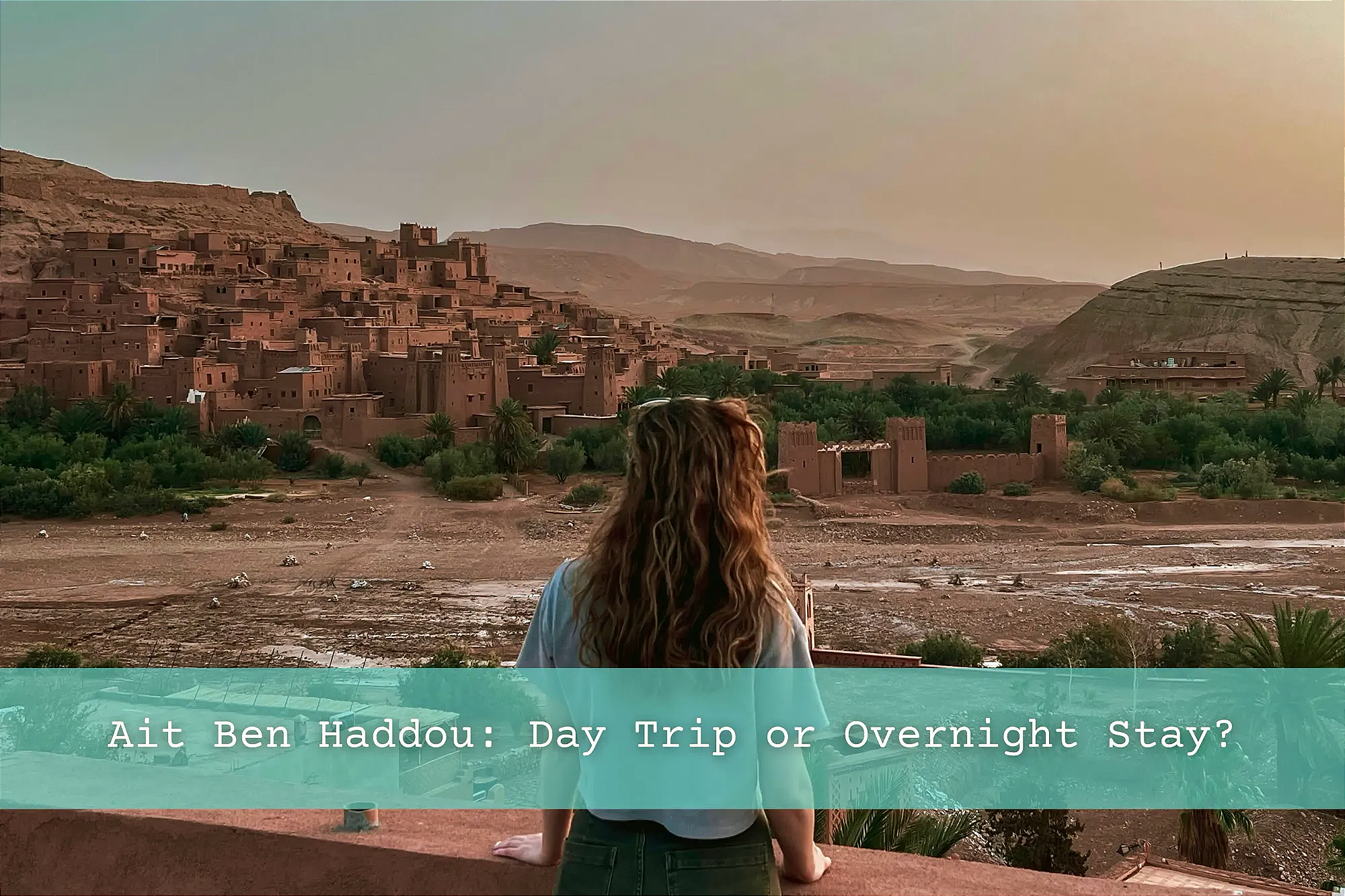 Girl standing on balcony overlooking Ait Ben Haddou at sunrise.