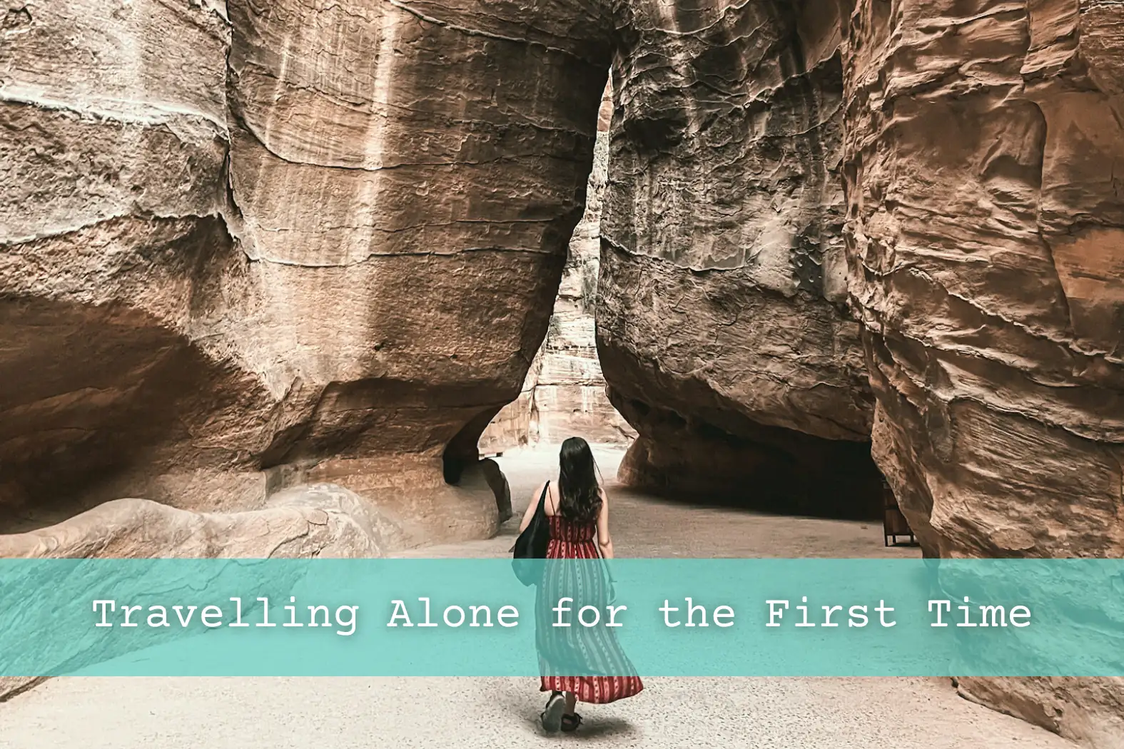 Girl walking on path carved out by the surrounding rocks on way to Petra in Jordan.